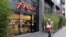 FILE - A woman walks past a store of French internet service provider and mobile phone operator 'Free' in Paris.