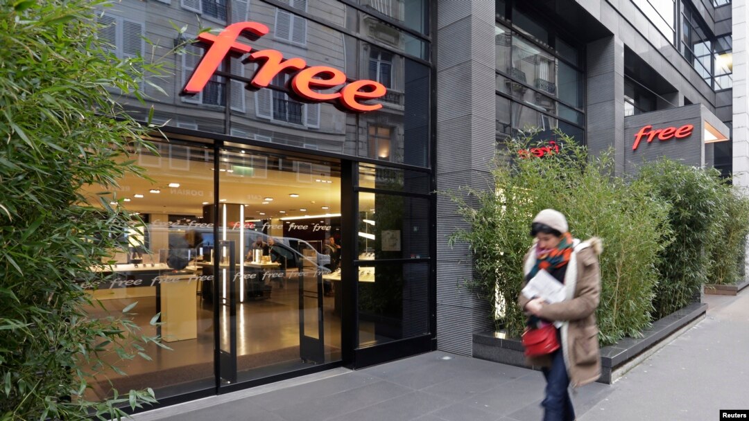 FILE - A woman walks past a store of French internet service provider and mobile phone operator 'Free' in Paris.