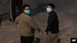 Hong Kong activists Joshua Wong, right, and Ivan Lam, left, are escorted by Correctional Services officers to prison, in Hong Kong, Dec. 2, 2020.