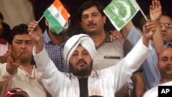 FILE - Indian pop star Daler Mehndi, center, waves Indian and Pakistani flags while watching a cricket match in Lahore, Pakistan, March 24, 2004.