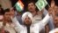 FILE - Indian pop star Daler Mehndi, center, waves Indian and Pakistani flags while watching a cricket match in Lahore, Pakistan, March 24, 2004.
