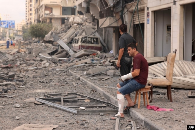 Palestinian men look at the destruction outside a damaged apartment building following Israeli airstrikes on Gaza City on October 10, 2023. (Photo by MAHMUD HAMS / AFP)