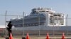 A photographer takes pictures near the quarantined Diamond Princess cruise ship, anchored at a port in Yokohama, Japan, Feb. 21, 2020.