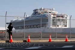 FILE - A photographer takes pictures near the quarantined Diamond Princess cruise ship, anchored at a port in Yokohama, Japan, Feb. 21, 2020.