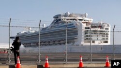 A photographer takes pictures near the quarantined Diamond Princess cruise ship, anchored at a port in Yokohama, Japan, Feb. 21, 2020.