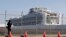 A photographer takes pictures near the quarantined Diamond Princess cruise ship, anchored at a port in Yokohama, Japan, Feb. 21, 2020.