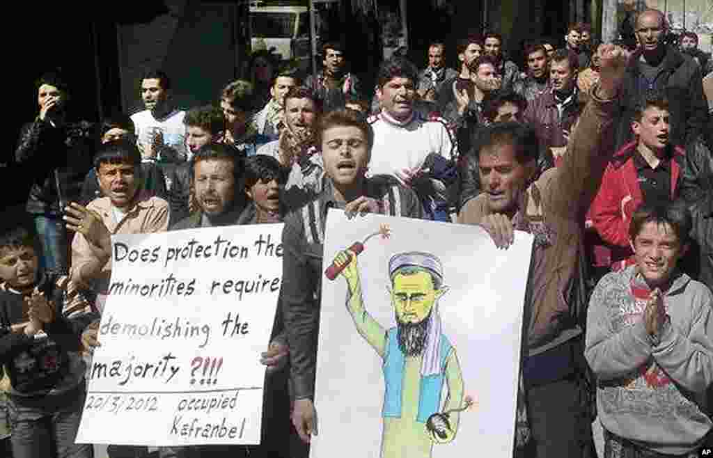 This citizen journalism image shows anti-Syrian regime protesters chanting slogans and holding a poster depicting Syrian President Bashar al-Assad as Osama bin Laden during a demonstration in Kafranbel near Idlib, March 20, 2012. (AP/Local Coordination Co
