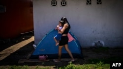 ARCHIVO - Una mujer migrante acampa con su hija mientras espera para tomar un bote hacia Colombia en Miramar, Panamá, el 5 de marzo de 2025.