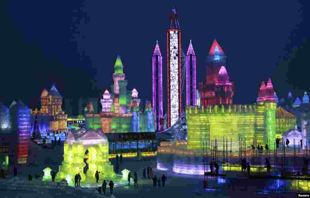 People visit newly-built ice sculptures illuminated by colored lights during a trial operation of the 16th Harbin Ice and Snow World in Harbin, Heilongjiang province, China, Dec. 22, 2014.