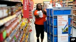 FILE - Walmart associate Alicia Carter fulfills online grocery orders in Houston, Nov. 9, 2018. Amazon and Walmart on April 18, 2019, kicked off a pilot program that lets shoppers on government food assistance in New York to shop and pay for their groceries online.