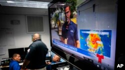 Emergency Center personnel stand next to a tv screen showing a meteorological image of the tropical storm Dorian, as they await its arrival, in Ceiba, Puerto Rico, Aug. 28, 2019. 