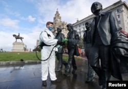 A worker disinfects a statue of the Beatles amid the coronavirus pandemic, in Liverpool, Britain, Oct. 1, 2020.