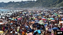 Pengunjung memadati pantai Bournemouth di Inggris selatan dan mengabaikan protokol kesehatan Covid-19, hari Kamis (25/6). 