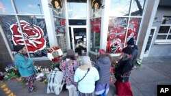 ARCHIVO - Varias personas se reúnen frente a un salón de tatuajes en la calle South Broadway, el martes 28 de diciembre de 2021, en Denver. El lugar fue uno de varios atacados por un sujeto que mató a 5 personas en distintos sitios de la ciudad, según la policía.