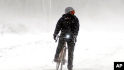 FILE - A bicyclist watches for traffic before riding in Fredonia, NY, on Dec. 11, 2009. 