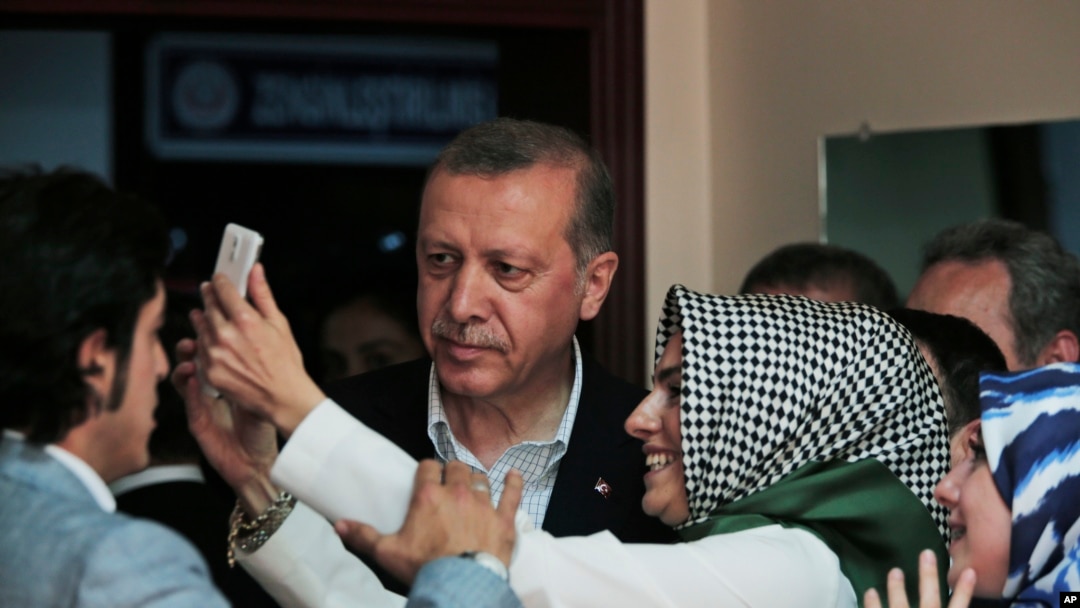 FILE - Turkish President Recep Tayyip Erdogan poses for selfie photograph with woman after voting at a polling station in Istanbul, June 7, 2015.