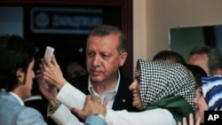 FILE - Turkish President Recep Tayyip Erdogan poses for selfie photograph with woman after voting at a polling station in Istanbul, June 7, 2015.