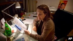 French journalist Ursula Gauthier, a reporter for the French news magazine L'Obs, holds a statement from the Chinese Ministry of Foreign Affairs as she sits at her desk in her apartment in Beijing, Dec. 26, 2015.