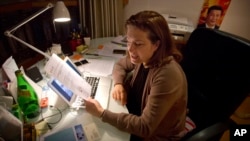 French journalist Ursula Gauthier, a reporter for the French news magazine L'Obs, holds a statement criticizing her from the Chinese Ministry of Foreign Affairs as she sits at her desk in her apartment in Beijing, Dec. 26, 2015.