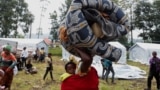 A Congolese woman carries her child as they flee from Goma, eastern Democratic Republic of Congo as they arrive at a reception center in Rugerero near Gisenyi, in Rubavu district, Rwanda, Jan. 28, 2025. 