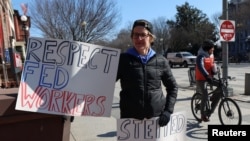 Seorang demonstran membawa poster berisi dukungan terhadap pekerja federal dalam aksi protes di luar Gedung Putih di Washington, pada 10 Februari 2025. (Foto: Reuters/Kevin Lamarque)