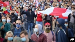 Warga membawa bendera national Belarus yang lama berpawai dalam demo oleh kelompok oposisi menentang hasil pemilihan presiden di Minsk, Belarus, 4 Oktober 2020.