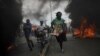 Para pengunjuk rasa berlari melewati ban-ban yang terbakar dalam demo menuntut pengunduran diri Presiden Haiti Jovenel Moise, di Port-au-Prince, Haiti, Rabu, 18 November 2020. (Foto:Andres Martinez Casares/Reuters))