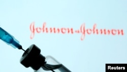 A vial and sryinge are seen in front of a displayed Johnson&Johnson logo in this illustration taken Jan. 11, 2021.