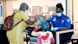 TSA agent Patrisa Johnson assists travelers as they clear security for flights out of Love Field in Dallas, Texas, June 24, 2020.