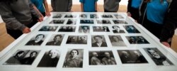FILE - A group of school pupils gather around a display of photographs of Gulag prisoners and victims of the Great Terror, on display at the Tate Modern in the Red Star Over Russia exhibition in London, Nov. 7, 2017.