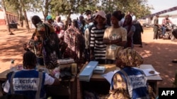 Officials from the Electoral Commission in Ghana check voters' IDs at a polling station in Walewale on Dec. 7, 2024, during the Ghana presidential and parliamentary elections.