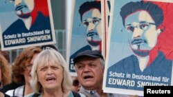 Para demonstran memegang poster-poster dalam unjuk rasa mendukung mantan kontraktor intelijen AS Edward Snowden di Berlin (4/7). Tulisan di poster bertuliskan "Tempat penampungan di Jerman untuk Edward Snowden". (Reuters/Tobias Schwarz) 