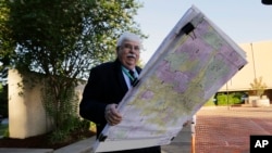 FILE - Russ Tidwell, a former lobbyist who is helping minority rights groups sue Texas over Republican-drawn voting maps, holds a set of maps as he makes his way to the federal court house, July 10, 2017.