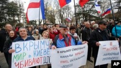 Pro-Russia demonstrators hold Russian and Crimean flags and posters as they rally in front of the local parliament building in Crimea's capital Simferopol, Ukraine, March 6, 2014.