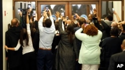 People rush the doors of the jury assembly room as former President Barack Obama departs after being dismissed from jury duty in the Daley Center, Nov. 8, 2017, in Chicago. 