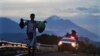 Archivo - Un migrante camina por una carretera, seguido por un vehículo de la Guardia Nacional Mexicana, en las afueras de Huixtla, estado de Chiapas, México, el 9 de junio de 2022.