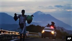 Archivo - Un migrante camina por una carretera, seguido por un vehículo de la Guardia Nacional Mexicana, en las afueras de Huixtla, estado de Chiapas, México, el 9 de junio de 2022.