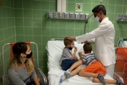 FILE - A nurse takes the temperature of children after being vaccinated against COVID-19 with a Cuban vaccine, at Juan Manuel Marquez hospital in Havana, August 24, 2021.