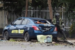 A member of the Indonesian anti-bomb unit collects evidence after a bomb exploded in Makassar, March 28, 2021.