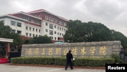 A man lays a bouquet of flowers at an entrance to the Wuxi Vocational College of Arts and Technology following a knife attack, in Wuxi, Jiangsu province, China, Nov. 17, 2024. 