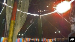 A young Nepalese girl trains on the trapeze using poor safety equipment as rain leaks through the roof, in one of India's traveling circuses, in Dehradun, India, July 2011