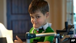 Braden Scott gives a thumbs up as he pauses while practicing on the piano in Tomball, Texas, March 29, 2019. Braden was diagnosed with the syndrome called acute flaccid myelitis, or AFM, in 2016 and was paralyzed almost completely.