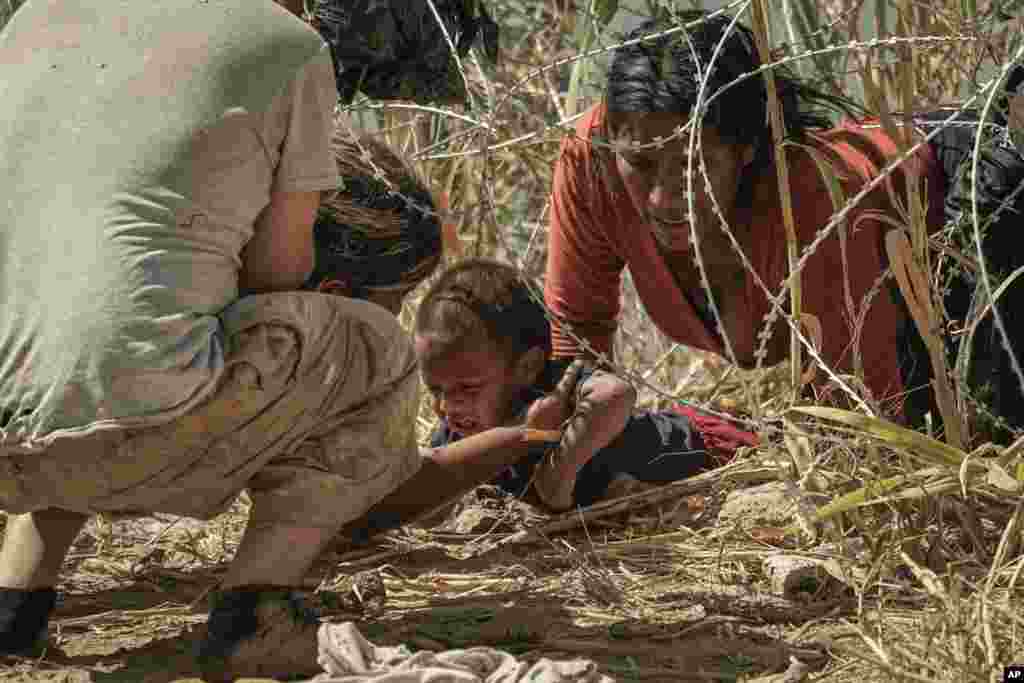 Los migrantes cruzan a Estados Unidos desde México pasando por debajo del alambre de concertina a lo largo del río Grande, el jueves 21 de septiembre de 2023, en Eagle Pass, Texas. [Foto: Eric Gay]