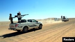 FILE - Forces loyal to Syria's President Bashar al-Assad ride on pickup trucks mounted with weapons in the Badia, in the southeast Syrian desert, in this handout picture provided by SANA, June 13, 2017.