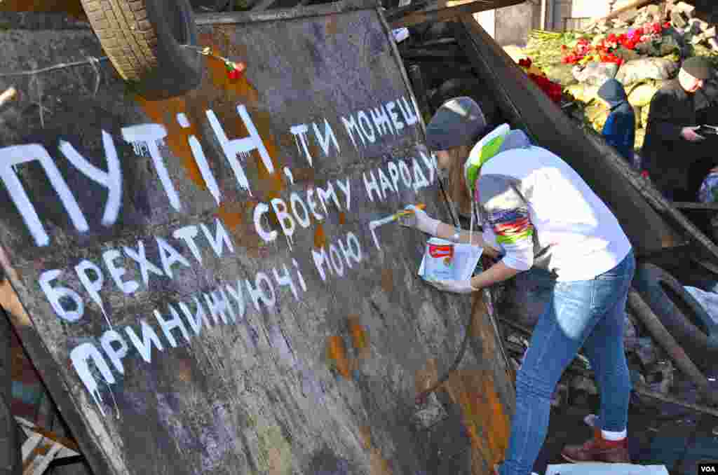 The girl is painting a slogan that reads "Putin you can kill us but you can't take away our freedom" in Kyiv's Independence Square, Ukraine, Mar. 8, 2014. (Jamie Dettmer/VOA)