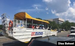 Tourists take photos of the U.S. Capitol (not seen) from a tour boat-like bus on a hot day in Washington, DC. (Photo by Diaa Bekheet)