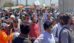 资料照片：人们聚集在喀布尔机场外向美国军人展示着文件。