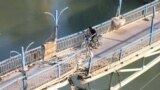 A rebel fighter and a child cross a damaged bridge in Syria&#39;s eastern town of Deir Ezzor.