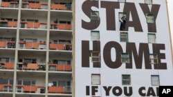 A billboard is installed on an apartment building in Cape Town, South Africa, Wednesday, March 25, 2020, before the country of 57 million people, will go into a nationwide lockdown for 21 days from Thursday to fight the spread of the new coronavirus.