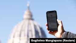 A man shows the 'Click to Pray' app, a smartphone app designed to allow the faithful to pray with a click, near St. Peter's Square at the Vatican, October 19, 2021. (REUTERS Photo/Guglielmo Mangiapane)